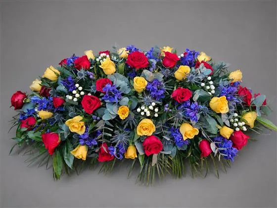 Rose & Delphinium Casket Spray — Red roses, yellow roses, blue delphinium, white Hypericum berries and thistle, finished with eucalyp