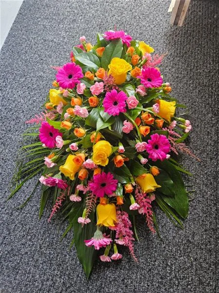 A Modern Tribute in Vibrant Blooms — A modern casket spray with vibrant blooms and lush greens. Celebrate life beautifully with this hear
