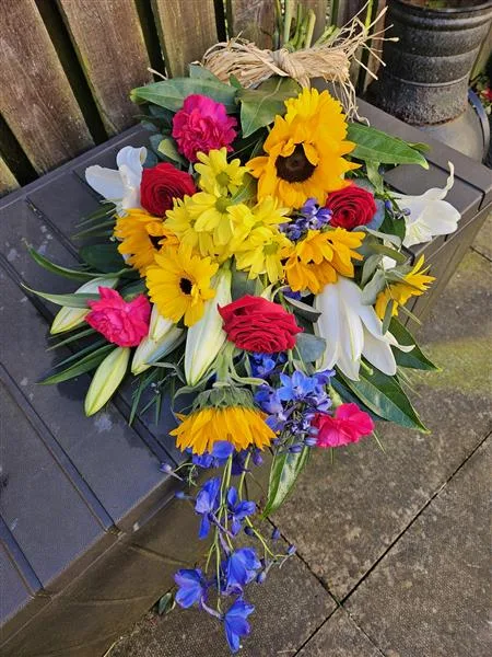 Vibrant Tied Sheaf — A bright tied sheaf of sunflowers, red roses, pink carnations, yellow gerberas and white lilies with