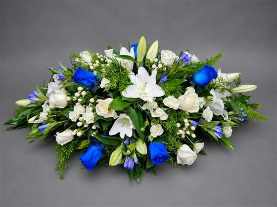 Blue Roses and White Lilies Casket Spray — A casket spray featuring blue roses and white lilies creates a serene and elegant tribute. The combi