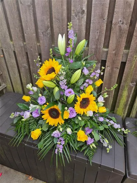 Pure Grace Yellow and Lilac Pedestal Tribute — Celebrate a life with the radiant charm of sunflowers and yellow roses, paired with the soothing pre
