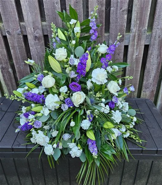 Soft Lilac Symphony Pedestal — This arrangement is a harmonious blend of lilac larkspur and purple lisianthus, woven among pristine