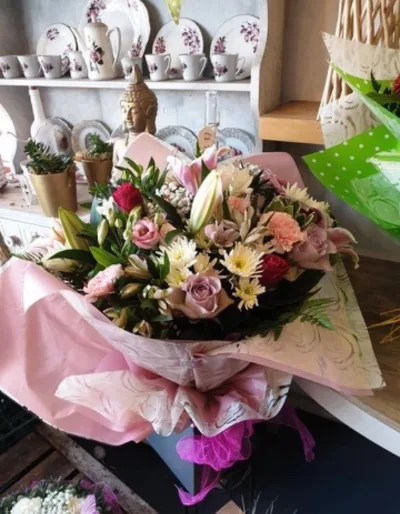 The Rosé — Soft pink and peach roses with lilies and seasonal blooms, wrapped in blush pink.