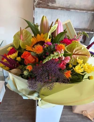 The Autumn Blaze — Sunflower, orange lilies, anthurium and purple trachelium in warm autumn tones.