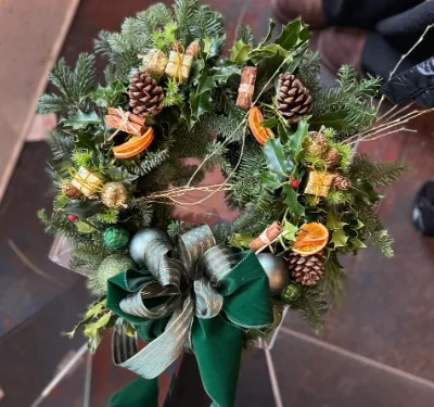 The Evergreen — Fresh foliage with pine cones, dried orange slices and little wrapped gifts, finished with a green v