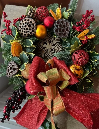 The Scarlet — Holly and fresh foliage with oranges, red berries and baubles, finished with a red and gold bow.