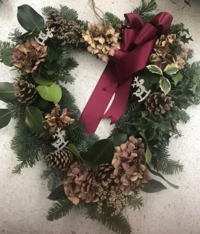 The Hydrangea — Dried hydrangea, pine cones and variegated holly with reindeer details and a burgundy bow.