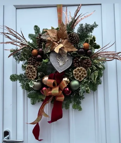 The Burgundy Star — A door wreath of fresh foliage with pine cones, copper baubles and a heart, finished with a burgundy