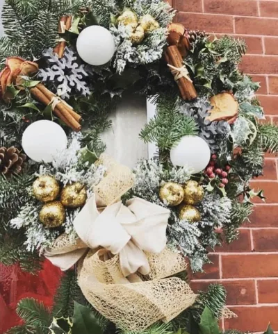 The Snowy — Frosted foliage with white baubles, cinnamon sticks and golden accents, finished with a cream bow.